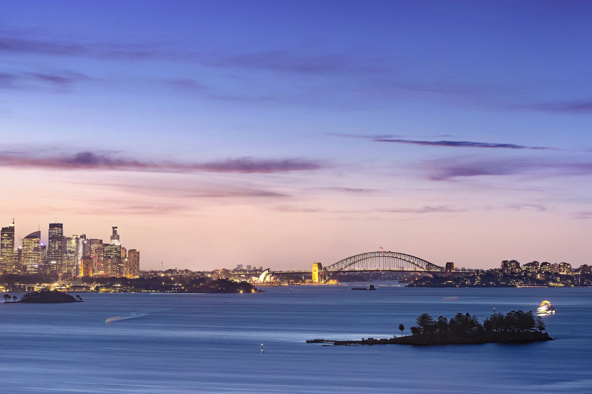 Sydney Harbour at dusk: the city, the Opera House and the Harbour Bridge across the water